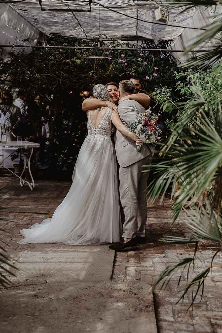 Zeremonienmeisterin für Hochzeit, Nicole Dirks, mit einem Hochzeitspaar in einer freundschaftlichen Umarmung.